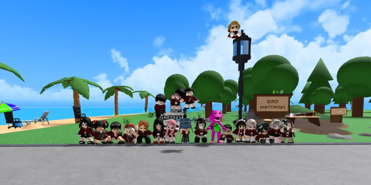 A long row of KU members in maroon uniforms crouched on the grass by a lamp post, one of them perched on top of it