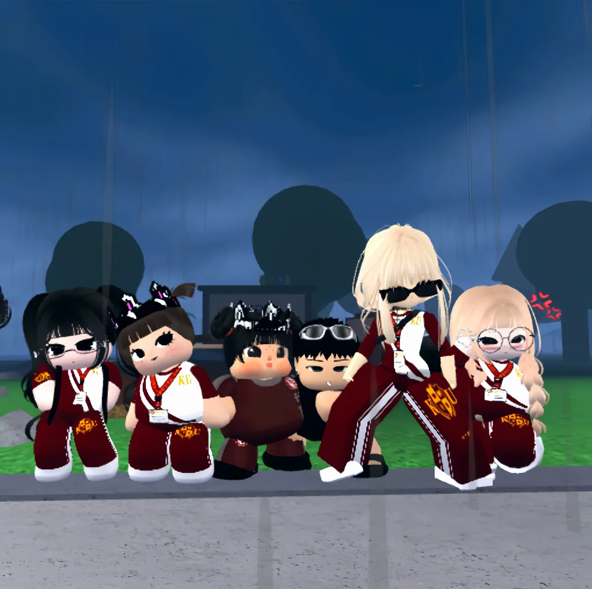Six friends in maroon and white KU tracksuits posing in the rain at night